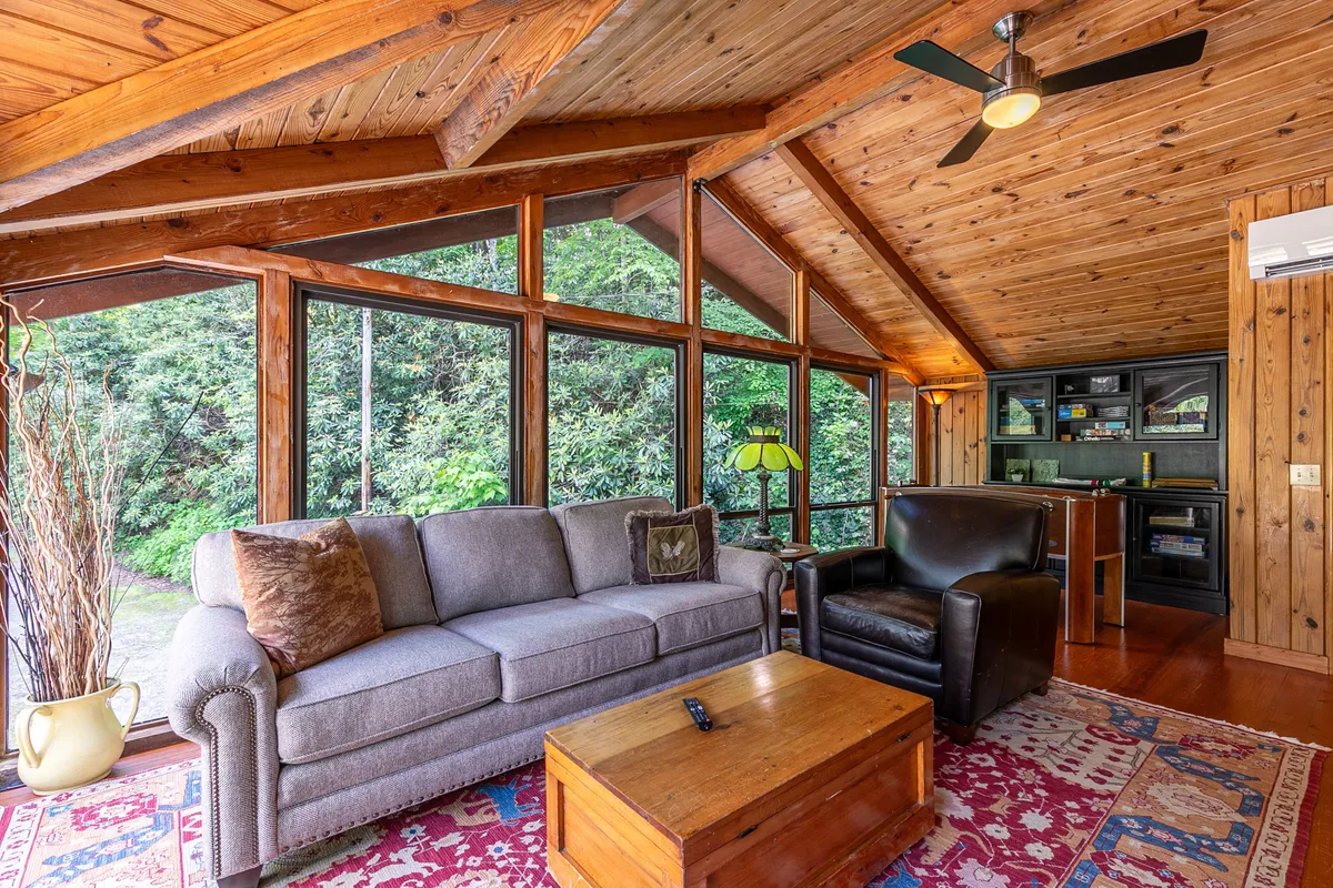 A comfortable sitting area featuring a sofa, armchair, coffee table, and large windows letting in natural light. The space is perfect for relaxing, reading, socializing, or enjoying nature views, with a warm and welcoming ambiance.