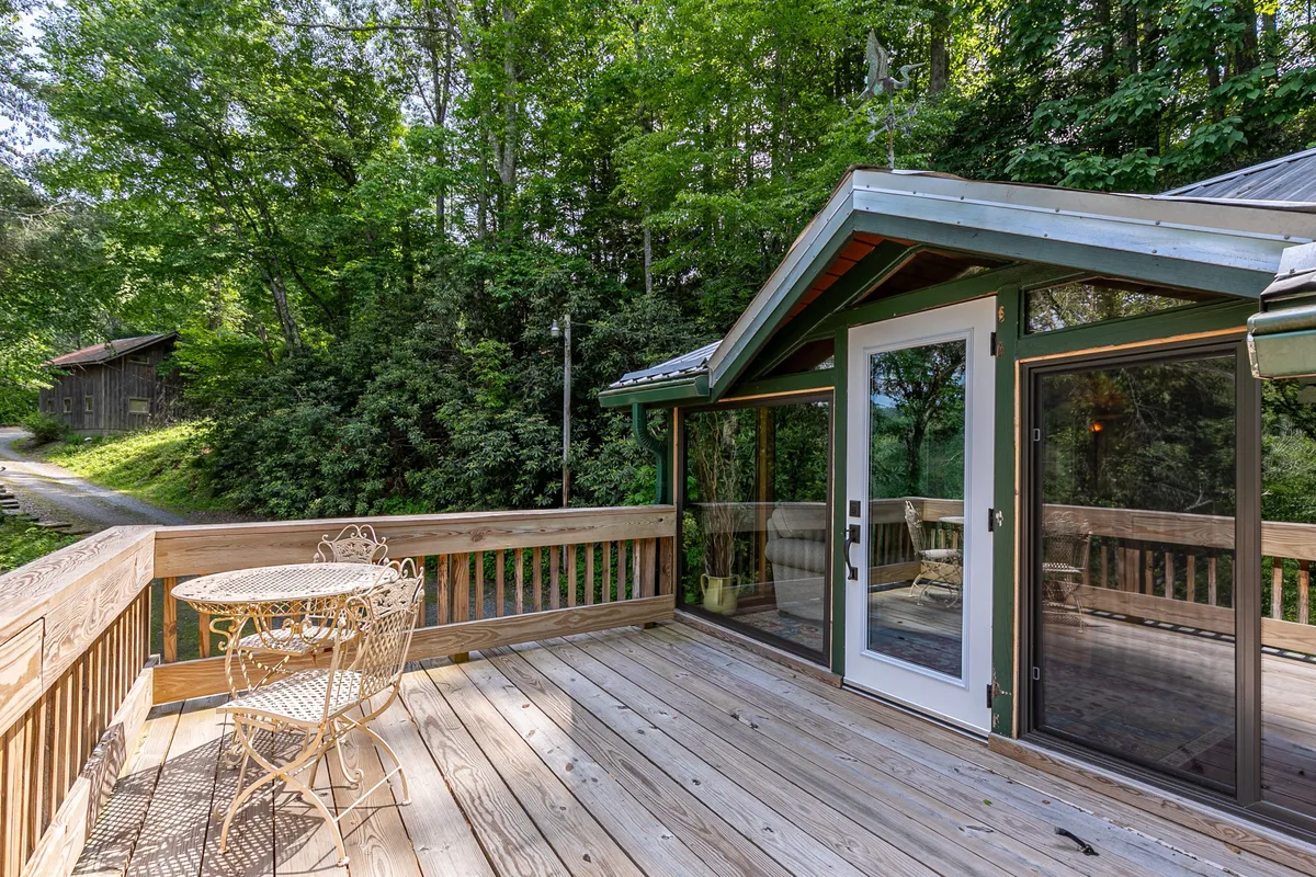 A cozy wooden deck set amid lush greenery, featuring a small round table perfect for relaxing and taking in the view. The deck is surrounded by trees, offering peaceful spots to unwind after outdoor adventures.